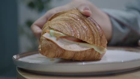 person eating a croissant sandwich