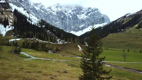 Aerial-drone-flight-at-scenic-Ahornboden-Engtal-valley-along-a-fir-tree-and-mountain-tops-in-the-Bavarian-Austrian-alps-on-a-cloudy-and-sunny-day-along-trees,-rocks,-forest-and-hills-in-nature