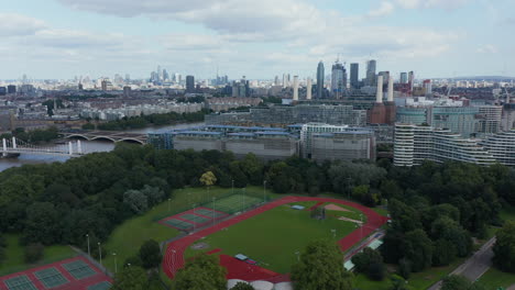 Aerial-view-of-Battersea-Park-sport-complex-and-modern-apartment-houses-at-Thames-river.-Tall-skyscrapers-in-background.-London,-UK