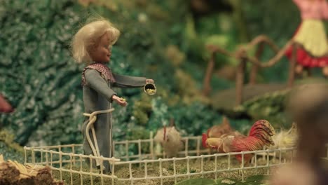 automated nativity scene figurine of a woman feeding chickens inside a fenced area