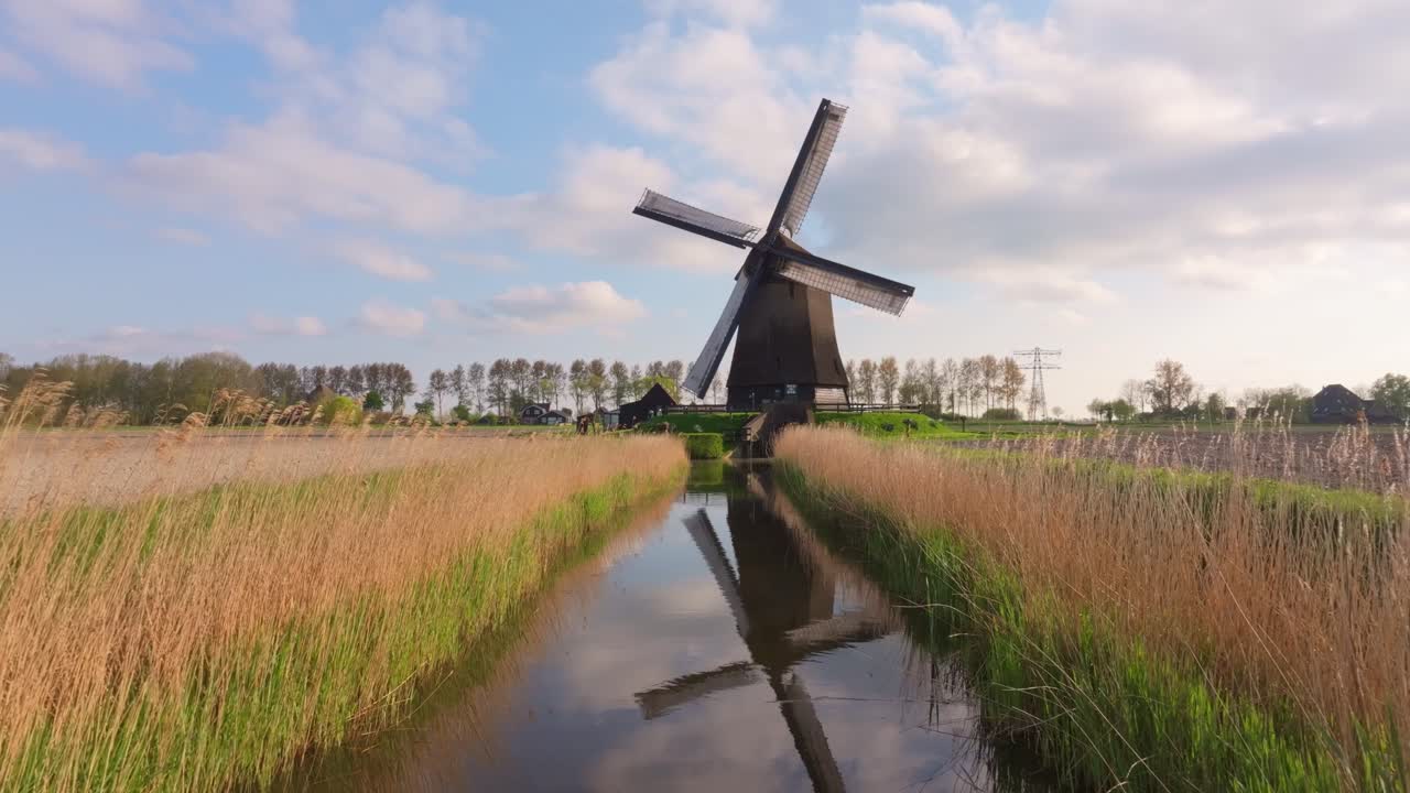 Flyfoto av en fungerende vindmølle som ruver i et landlig nederlandsk landskap.