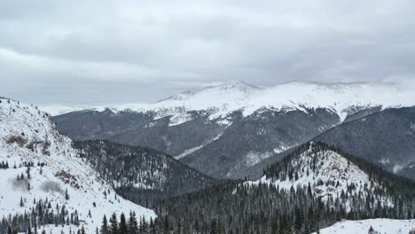 snowy mountain ranges with pine tree forest in winter park, colorado on a cloudy day