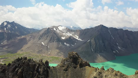 Circling-drone-shot-of-a-man-on-a-mountain-ridge-overlooking-the-Ala-Kol-lake-in-Kyrgystan