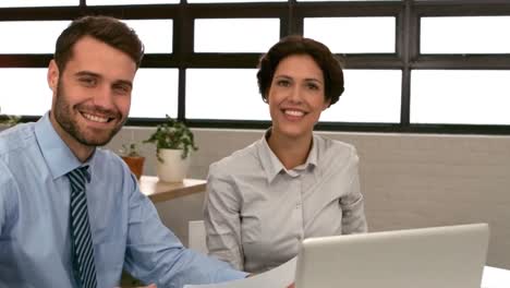 Business-couple-holding-document-and-smiling-at-the-camera