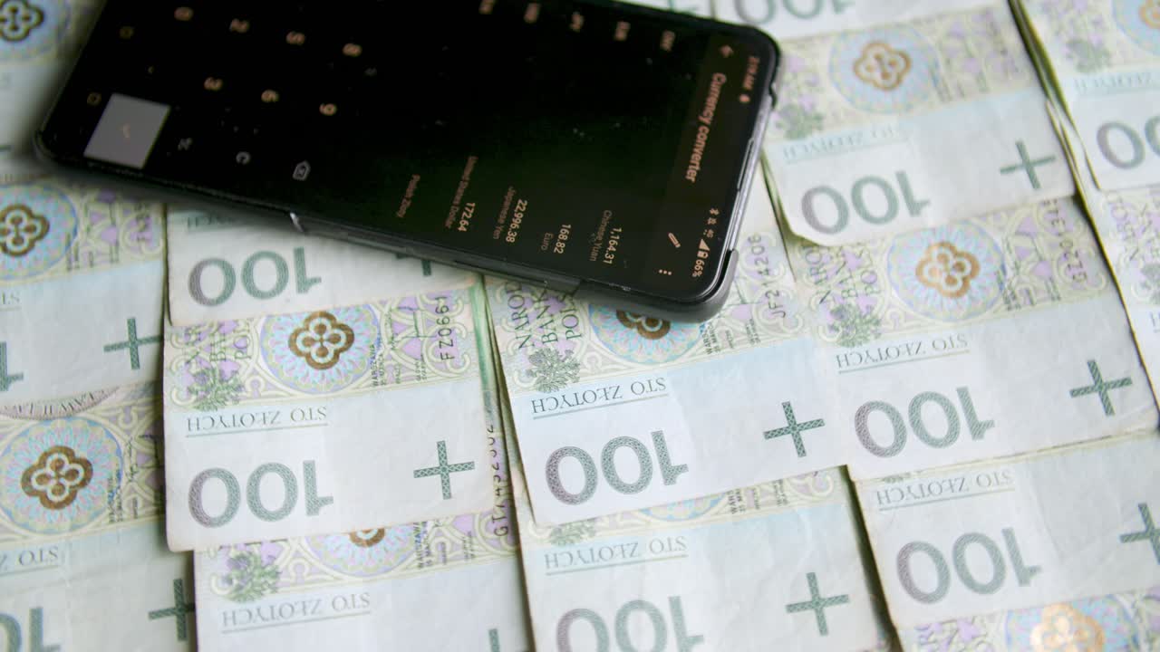 пачки банкнот на поворотном столе с курсами валют на смартфоне, обмен денег, подсчет расходов, домашние финансы, wymiana walut, учет польских денег, polskie pieniądze, złotówki