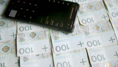 stacks of banknotes on a turntable with a currency rates on a smartphone, money exchange, expenses counting, home finances, wymiana walut, accounting polish money, polskie pieniądze, złotówki