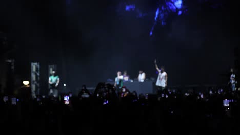 cantante en el escenario de conciertos al aire libre por la noche con fans frente a las luces brillantes del escenario, cámara lenta