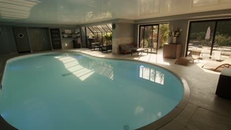 pan shot of an empty pool lit by natural light through windows