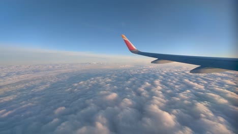 Flugzeugfensteransicht-Flugzeugflügel-Fliegt-An-Einem-Sonnigen-Nachmittag-über-Das-Wolkenmeer