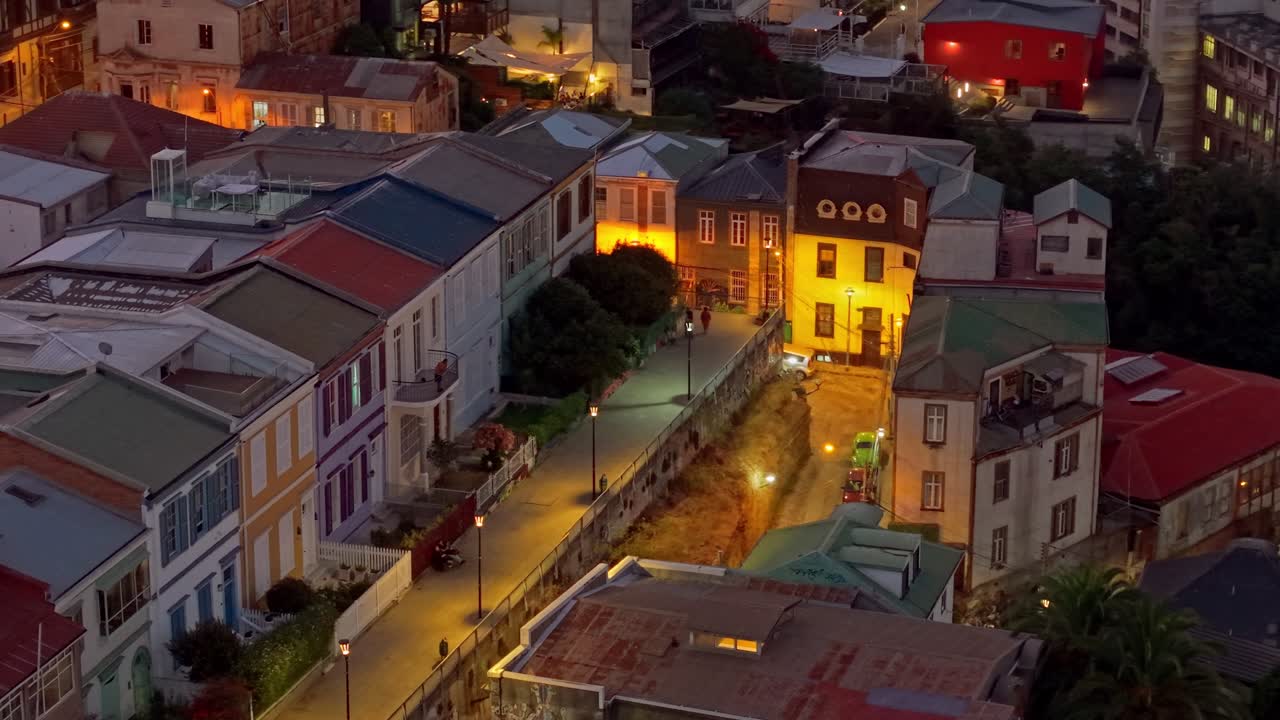 Imagem aérea com teleobjetiva da Atkinson Promenade à noite com arquitetura colorida e casais caminhando e compartilhando, Cerro Concepción, Valparaíso, Chile.