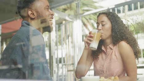 pareja feliz diversa pasando tiempo juntos en una cafetería, bebiendo café y hablando