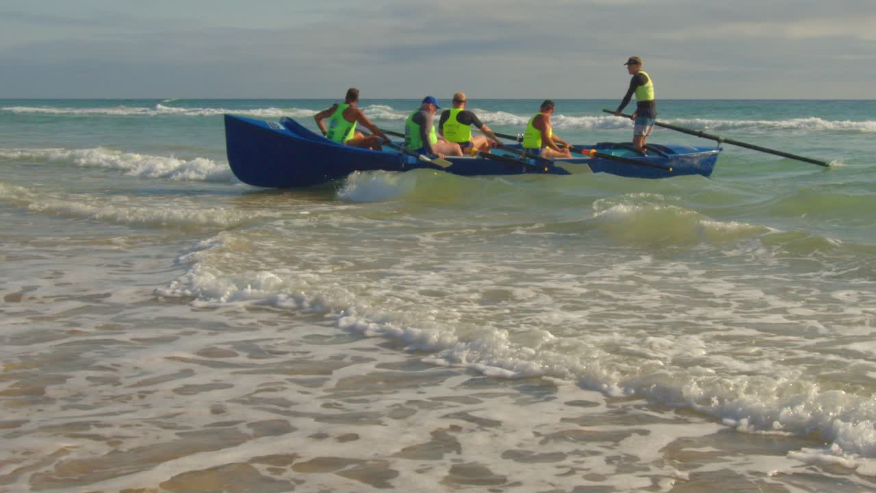 Australina Surf Lifesavers long boat riding a wave back onto the beach