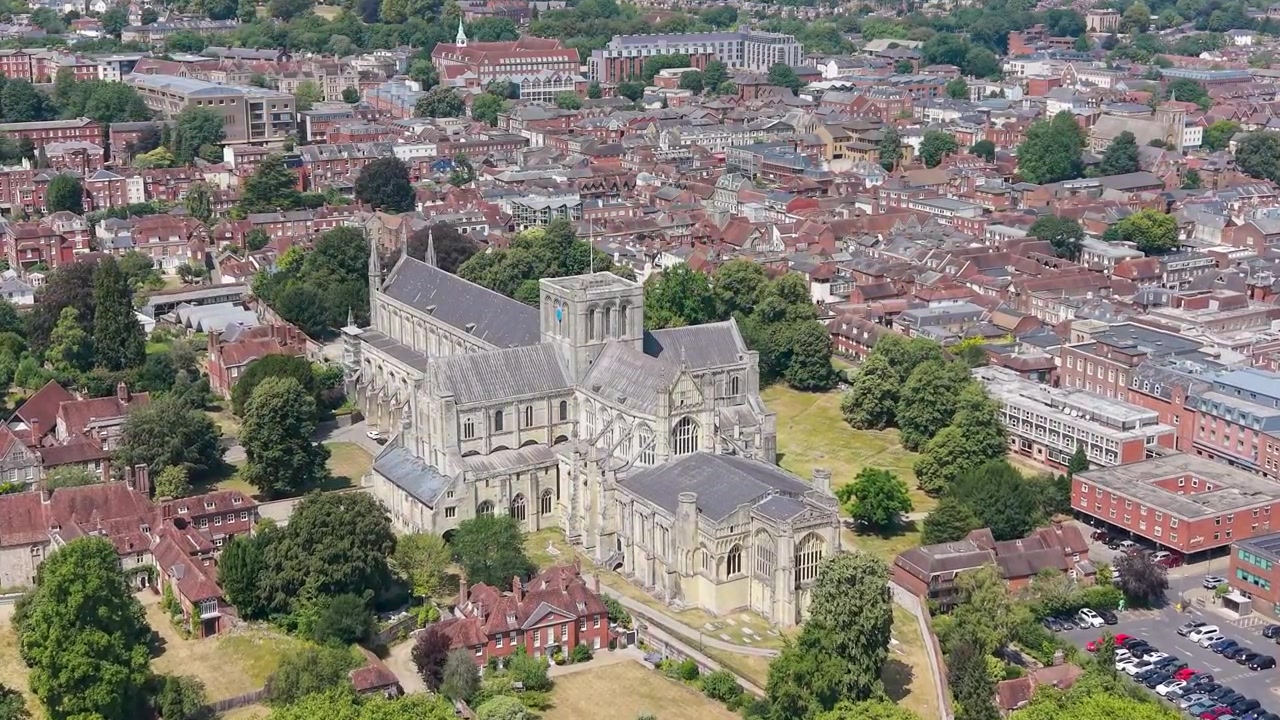 En flytur nærmer seg Winchester katedralens gotiske tårn, med det historiske engelske sentrum spredt ut bak på en solrik sommerdag