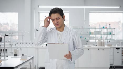 confused indian scientist writing observations on papers