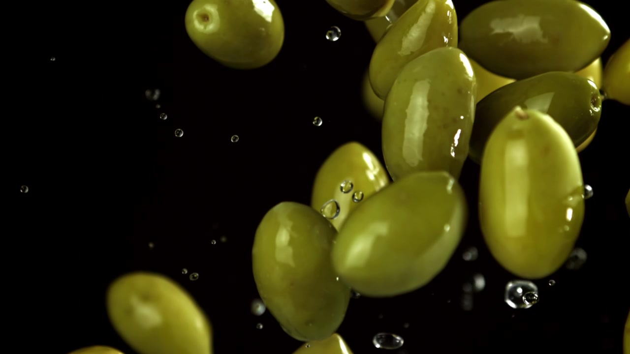 Super rallentatore di olive verdi che cadono con schizzi d'acqua