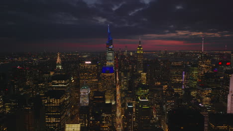 Statische-Panoramaaufnahme-Aus-Der-Luft-Von-Wolkenkratzern-In-Der-Innenstadt-Bei-Nacht.-Ein-Vanderbilt-Und-Ein-Empire-State-Building-Gegen-Einen-Farbenfrohen-Himmel.-Manhattan,-New-York-City,-Vereinigte-Staaten