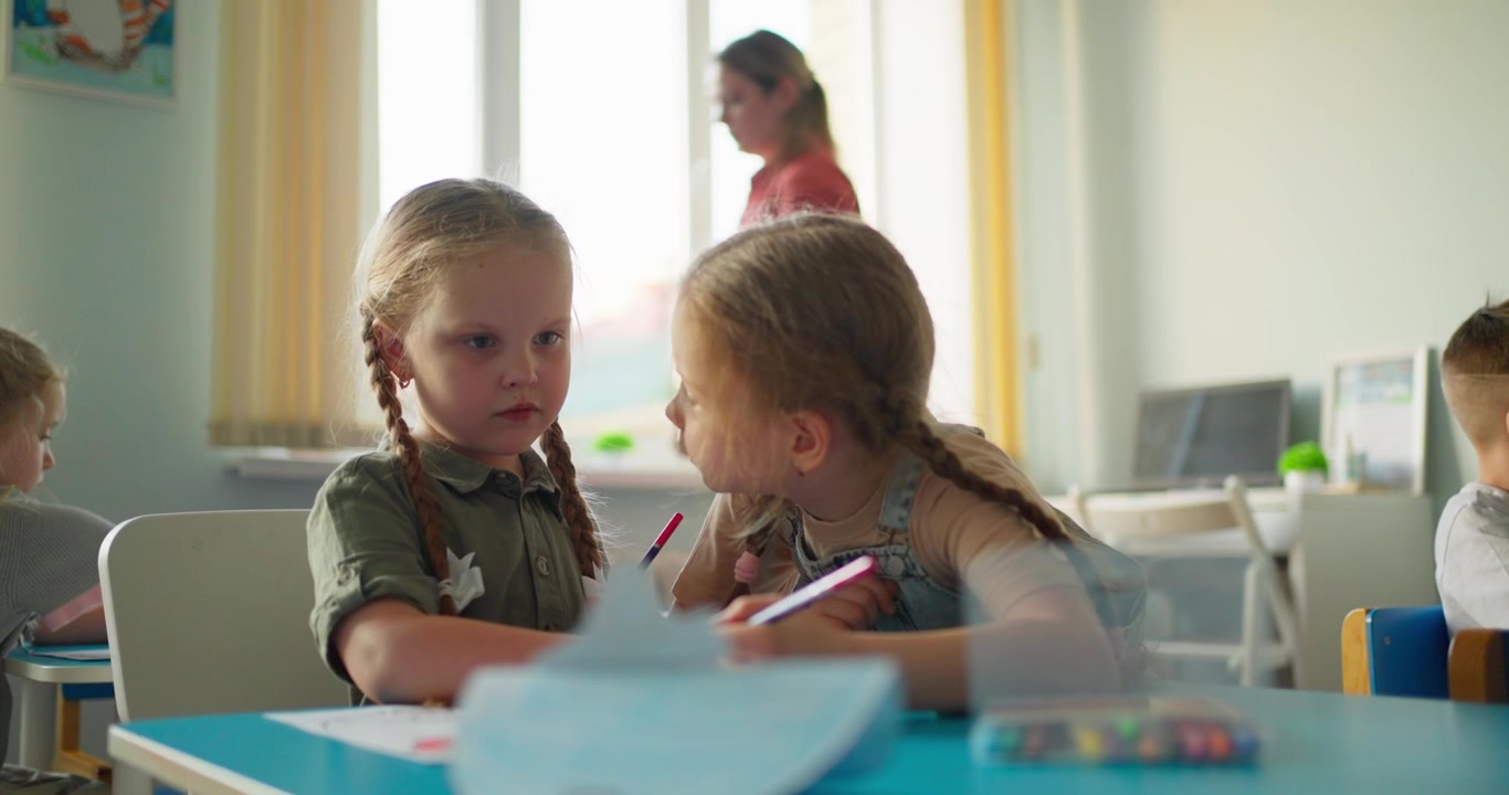 Two Young Girls Drawing and Learning Together in a Bright Classroom