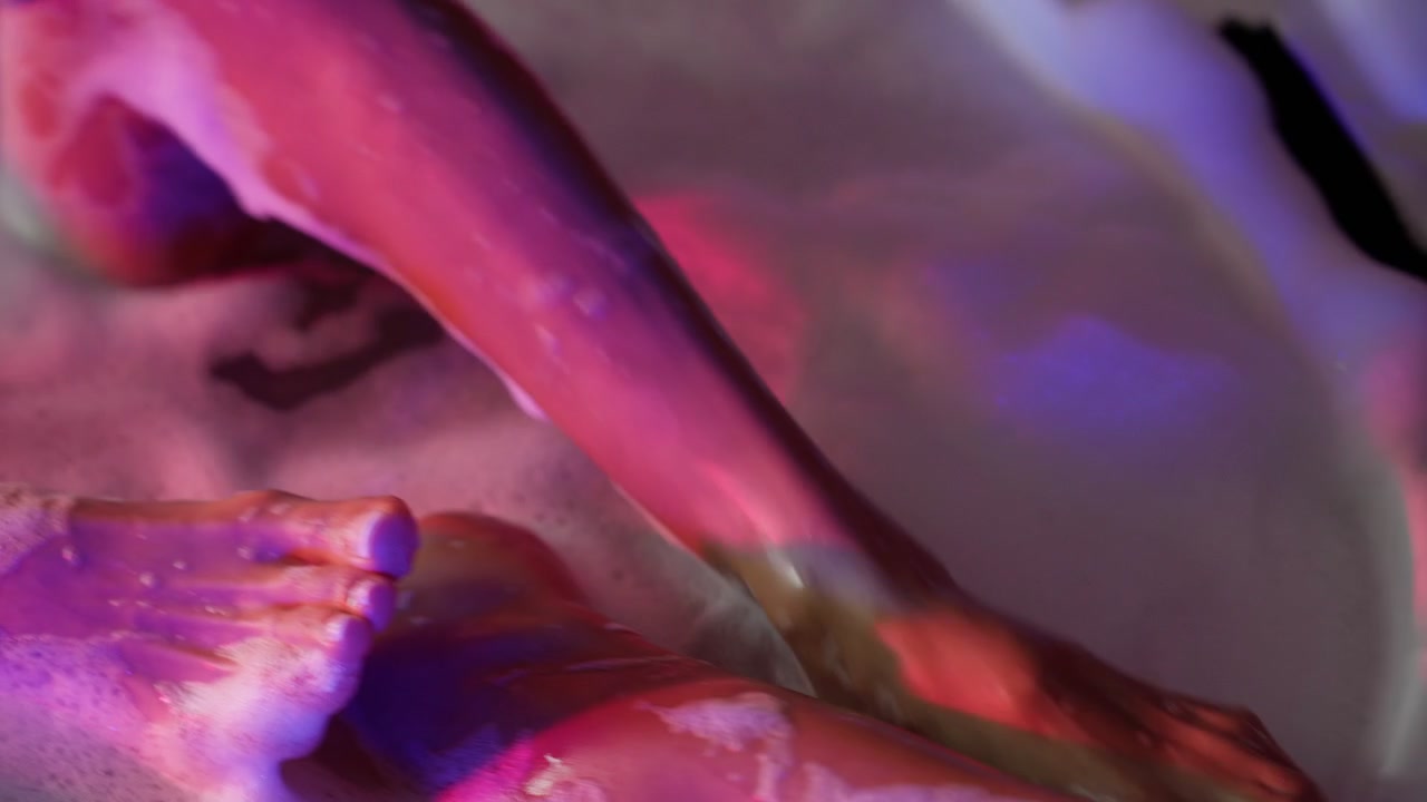 Person Relaxing in a Bubble Bath with Neon Lighting