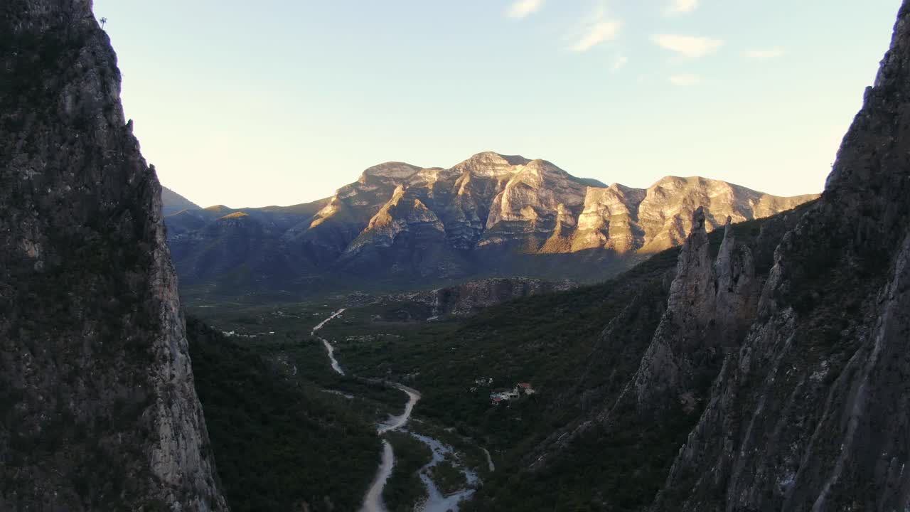 drone flying towards a golden hour mountain ridge on the horizon, river stream in valley, wide sunset aerial shot in Portrero Chico hills, mountains of Hidalgo, Mexico, Nuevo Leon