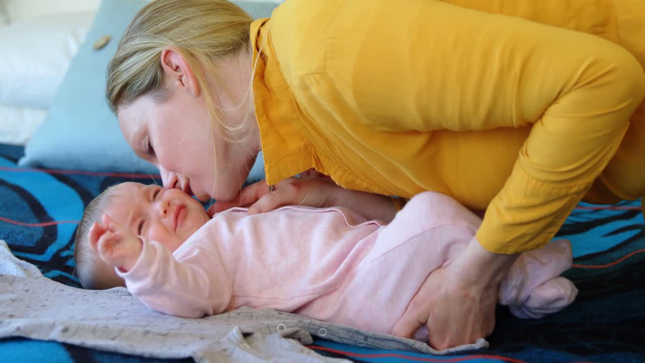 침대에 있는 아기에게 키스하는 엄마 4k
