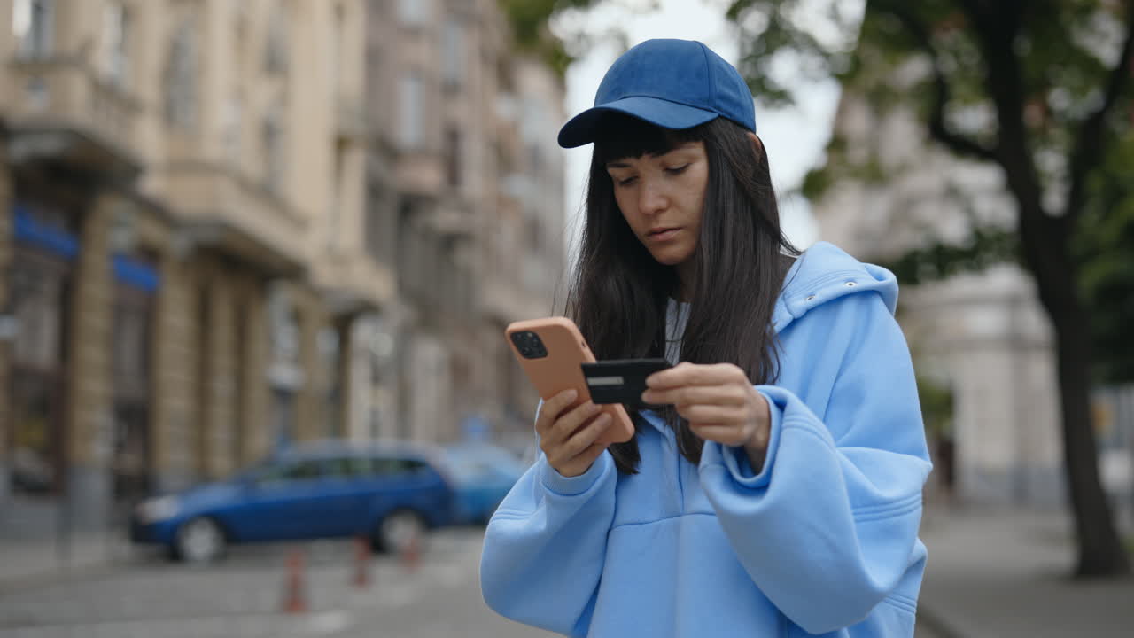 Woman using mobile phone and credit card on the street