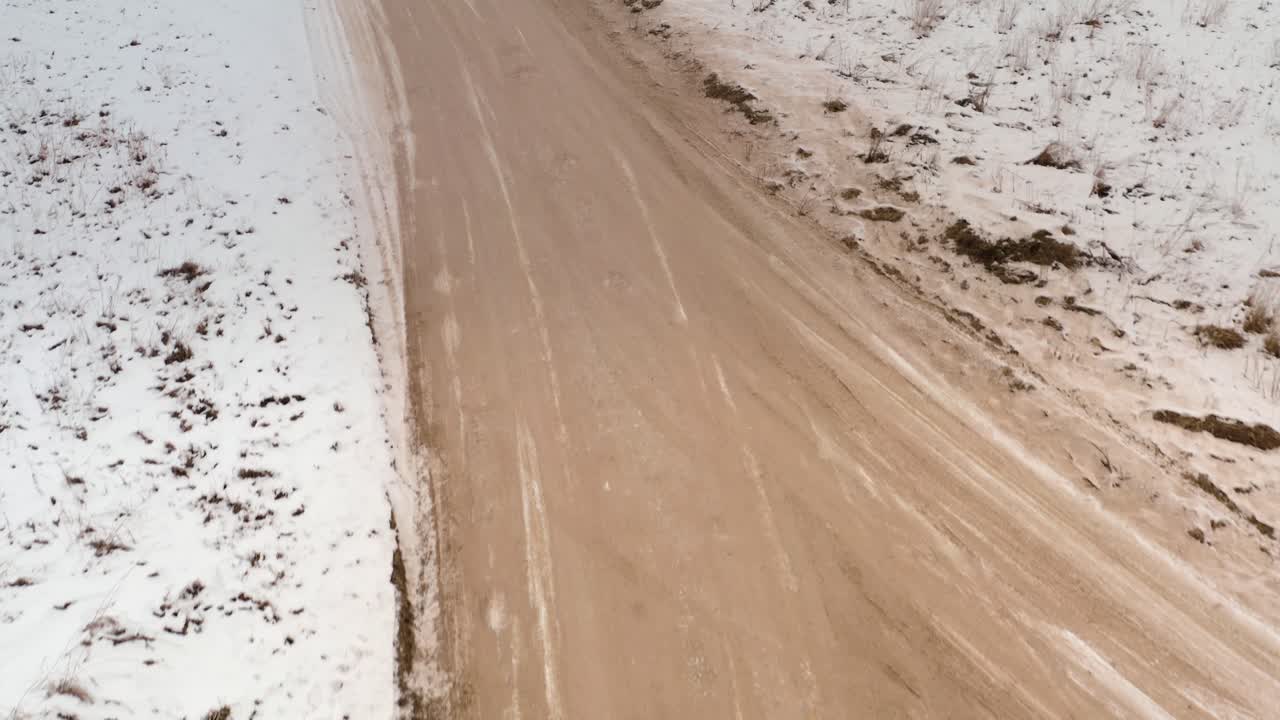 Aerial overhead drone shot of a gravel road winding through the countryside. Top down drone shot of a dirt road in rural landscape.