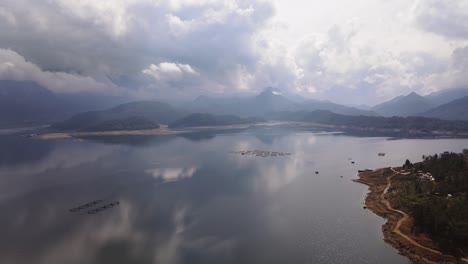 vista aérea sobre el lago de montaña con granjas de peces con muchos recintos de peces en jaulas