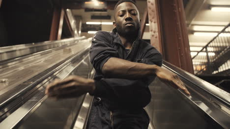 janitor dancer twists arms as escalator takes him up, medium closeup