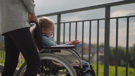 little girl sits in wheelchair pointing finger to high tower