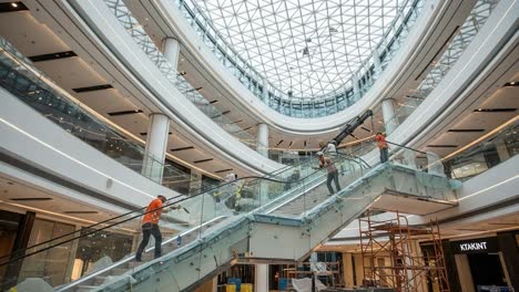 workers installing an escalator in a modern building with a glass dome ceiling