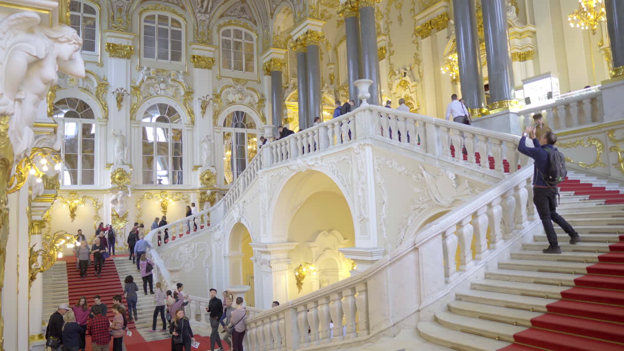 Royal looking hall and staircase covered with gold full of tourists in hermitage museum