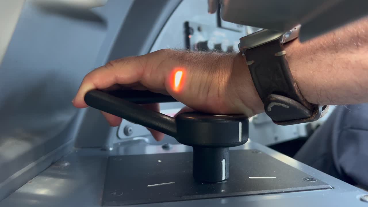 Extreme closeup view of the left hand of a white pilot, Captain side, handling the nose wheel steering of an airplane during taxi. Sunlight is bathing the scene. 4K 60FPS