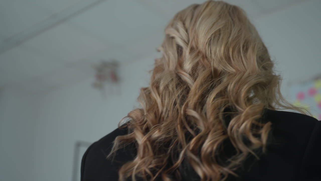 Confident real estate agent carries architectural building model through office, preparing to place it on her desk, captured in bright indoor setting with subtle professional expression