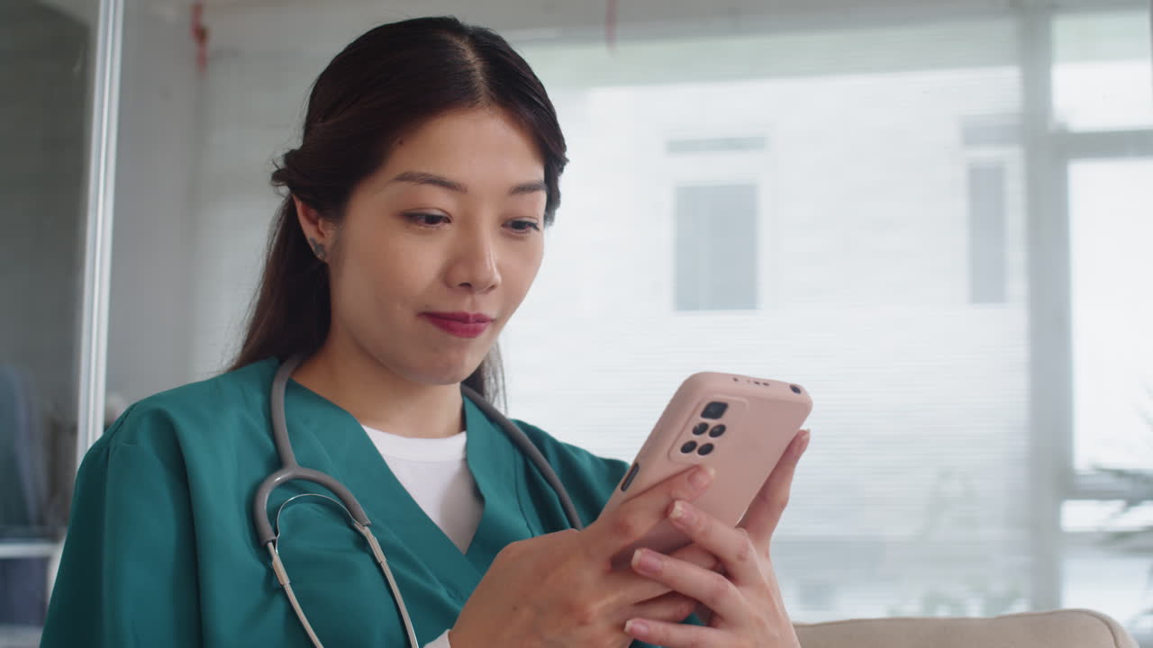 Nurse Chatting with Friends on Smartphone during Break at Work