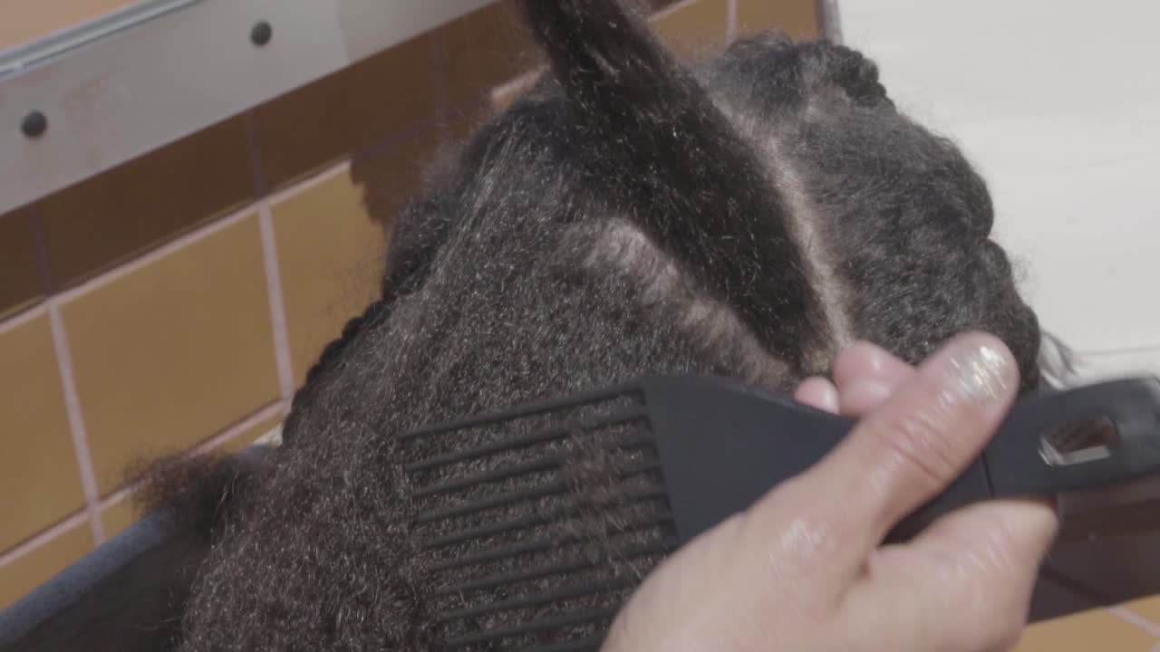 Slow motion of an african kid having her afro hair brushed