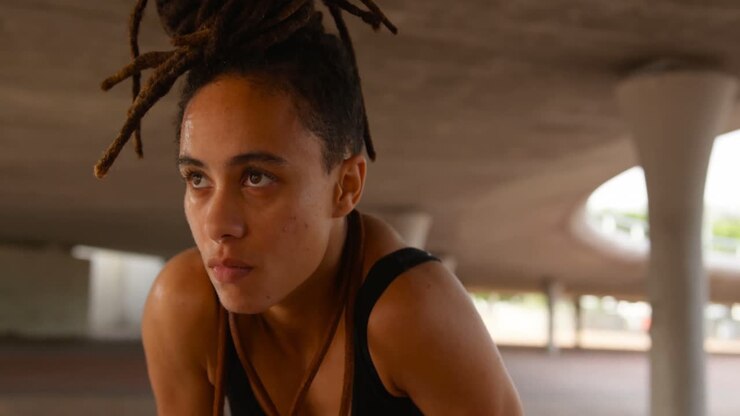 Vista frontale di giovane donna afroamericana che riposa dopo l'allenamento in città 4k