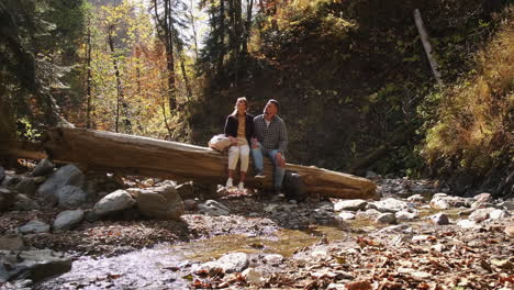 couple relaxing by a stream in autumn forest