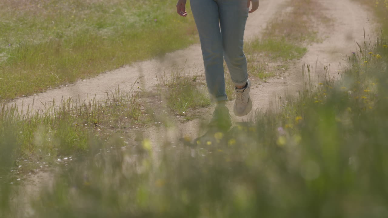 A woman walks peacefully along a quiet rural road surrounded by natural scenery, evoking solitude and connection with the outdoors