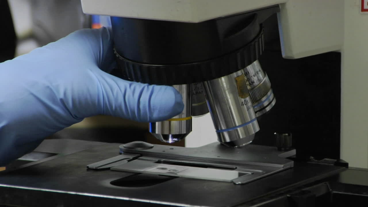 un técnico médico ajusta un microscopio