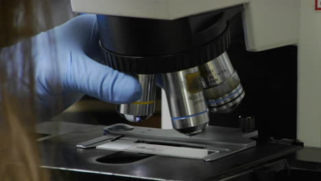 un técnico médico ajusta un microscopio