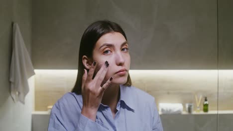 mujer aplicando crema para la cara en el baño
