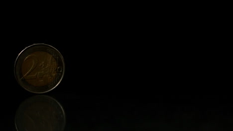 euro coin rolling over black surface