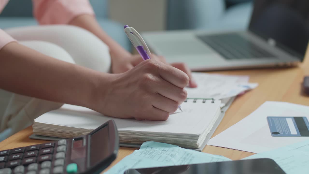 Close Up Of Woman'S Hand Recording The Expenses In Notebook