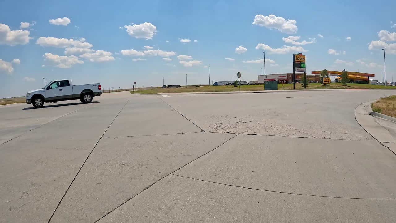 POV - Driving on the frontage road to pull into the truck entrances for Love's Travel Stop; preparing to get diesel for over-highway truck; concepts of logistics, road trip and highway transportation