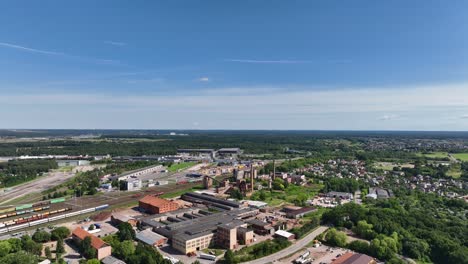 Aerial-view-of-old-and-abandoned-factory-buildings-and-chimneys-near-the-train-station-on-a-sunny-summer-day