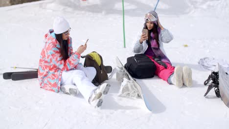 Young-female-friends-relaxing-with-snowboards