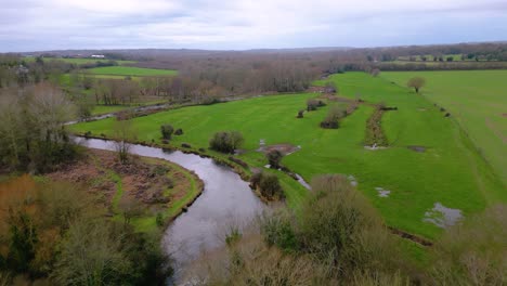 flight over river and small bridge in lush green southdowns countryside in winter no leaves on trees