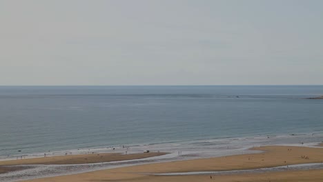 woolacombe bay beach panning shot of people swimming in beautiful blue sea and sky in summer