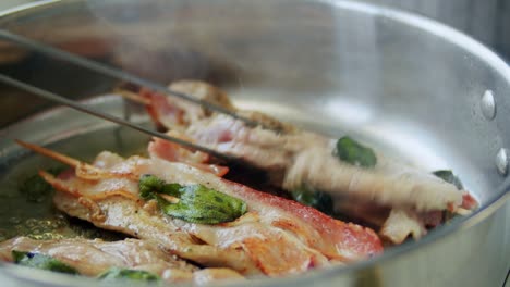 persona freyendo saltimbocca en palos de madera en una sartén