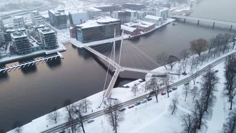 circling around a beautiful pedestrian bridge over the river drammenselva in town of drammen, norway during snowfall